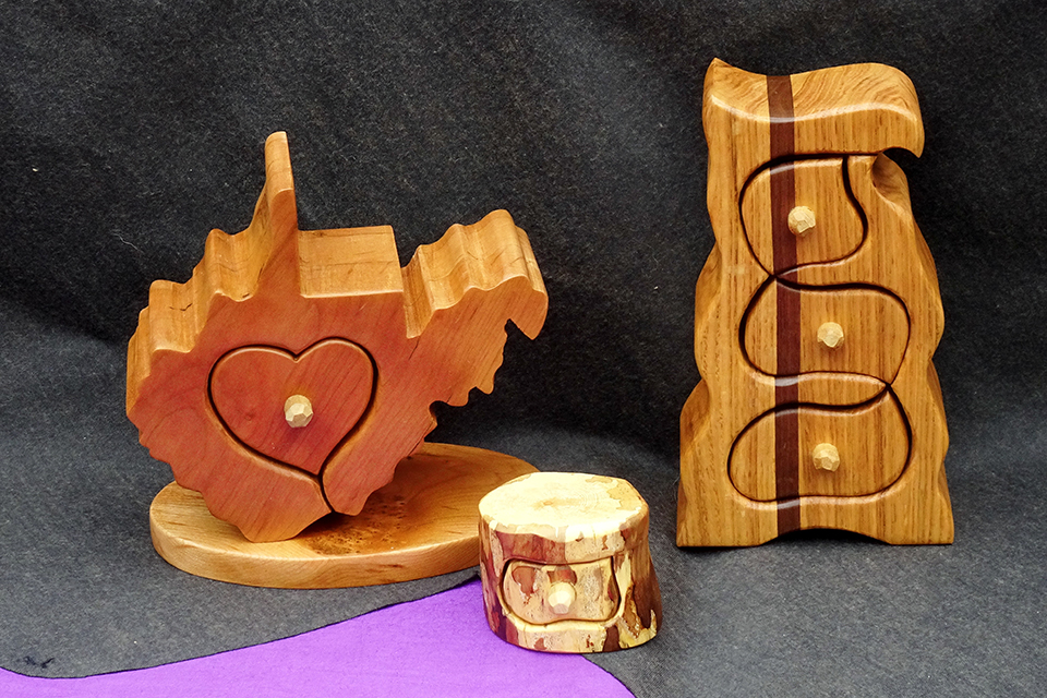 wooden boxes. one shaped like the State of West Virginia. The other is shaped like a chest of drawers.
