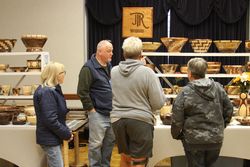 A group of patrons talk with the vendor at the J R Wood booth during the 2023 Mountaineer Week Arts and Craft Fair.