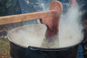 Apple butter being stirred in a kettle over an open flame