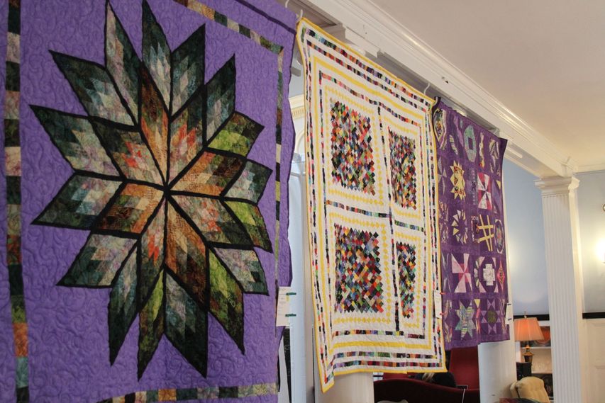 Purple and white quilts hung for viewing at the 2019 Quilt Show